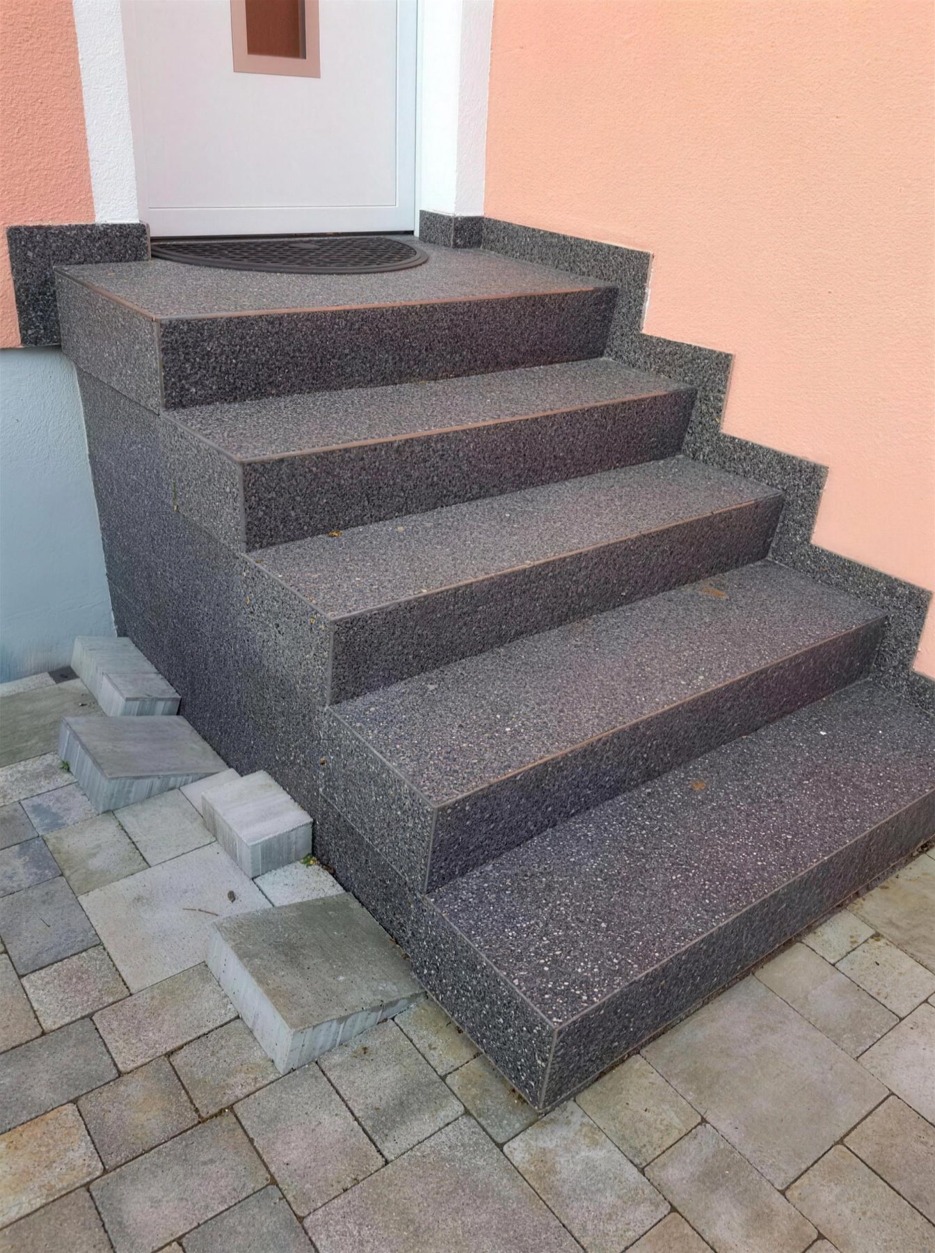 Echtes Kundenprojekt: Außentreppe mit grauem Steinbelag vor einer Haustür