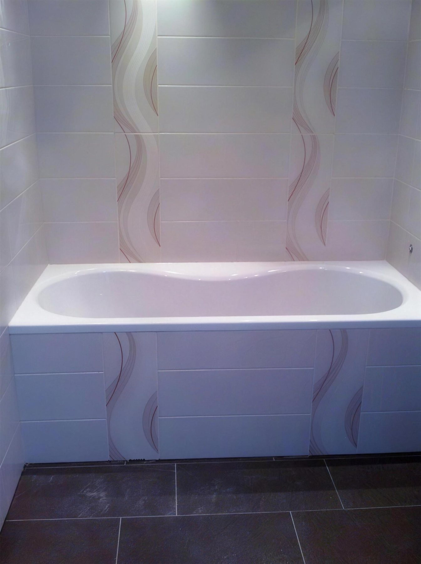 Echtes Kundenprojekt: Badewanne mit hellen Dekorfliesen und dunklem Fliesenboden